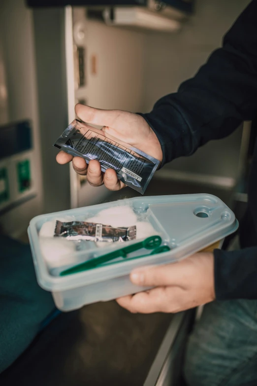 a man in black jacket holding a green toothbrush and cleaning it