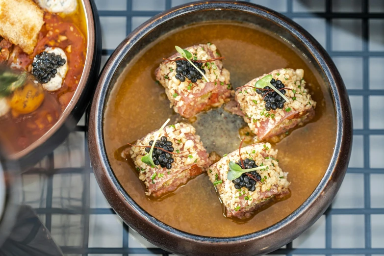 a bowl of food next to two dishes with soup and meat