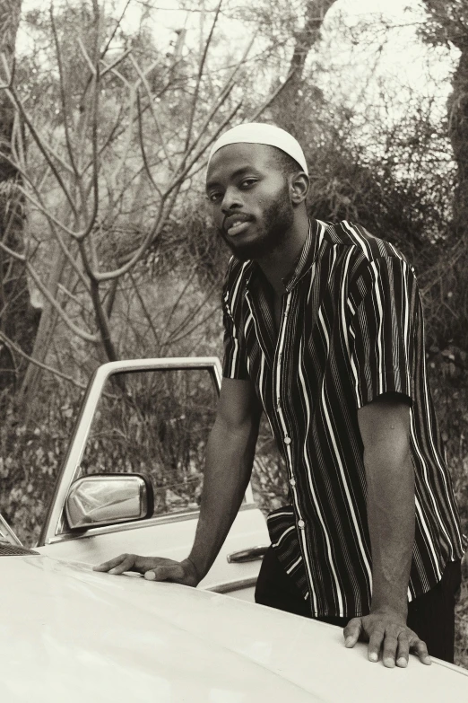 a black and white po of a man leaning on the hood of a pick up truck