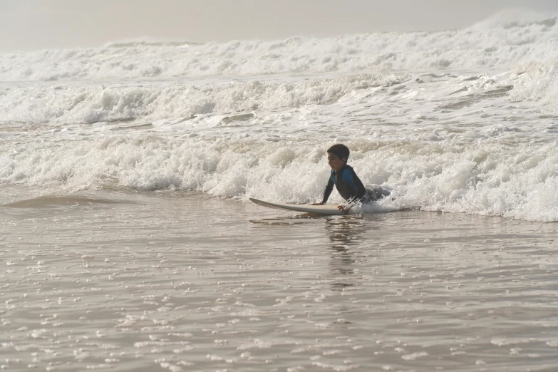 a young man surfing on a small wave