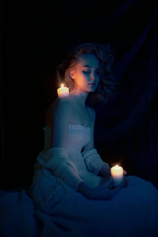 two lit candles illuminate an image of a  sitting in bed