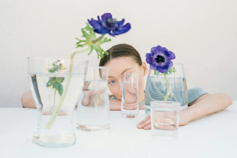 a woman is at the table looking over several vases and water glasses