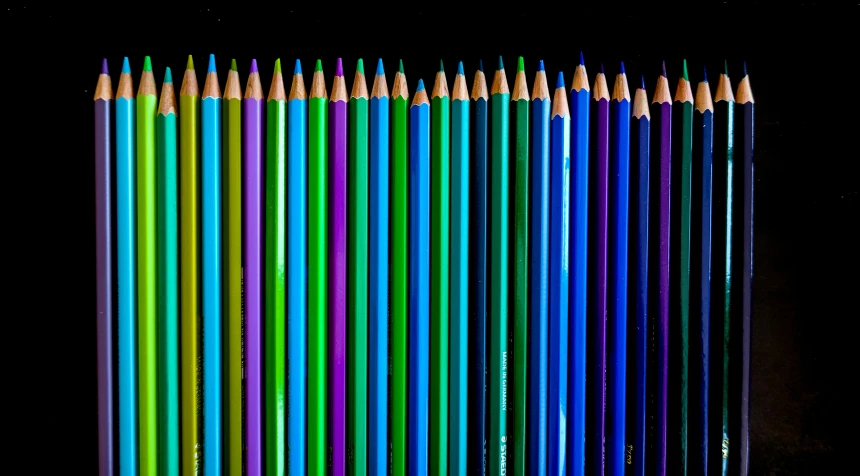 many colored pencils lined up on a table