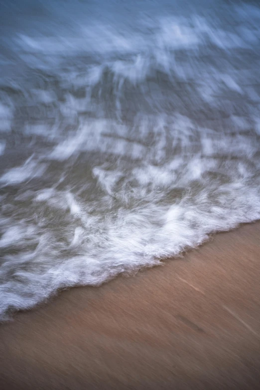 an ocean with sand and some waves rolling on the shore