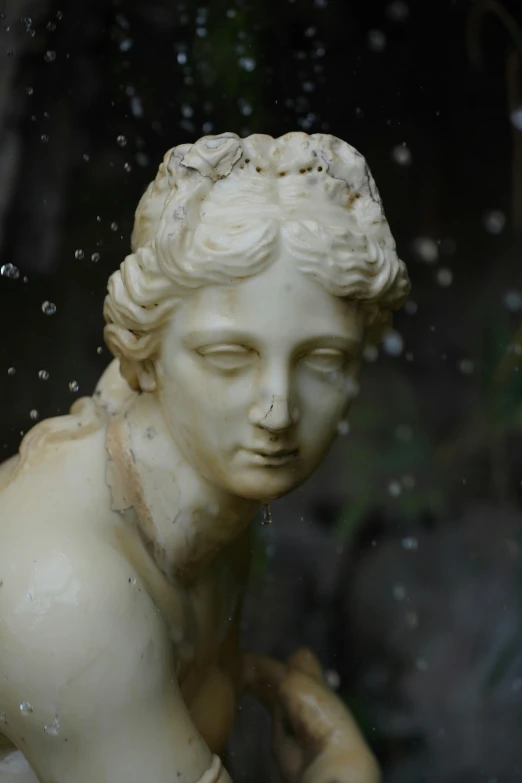 an old statue holding an apple under a rain