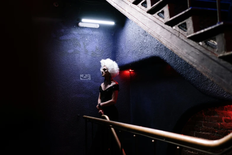 woman in red light under stairs, with white hair