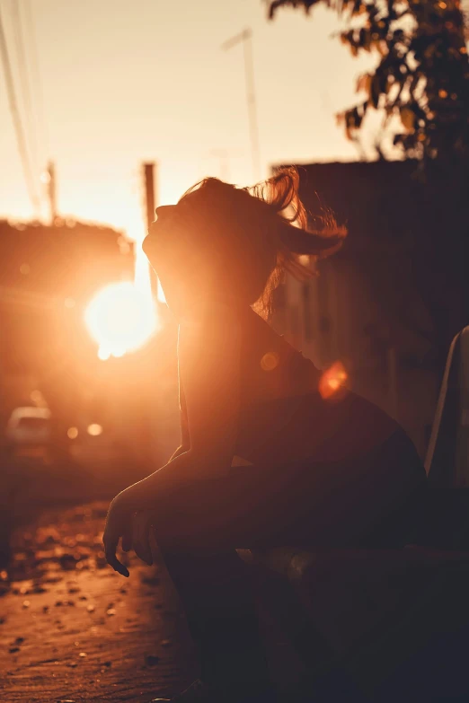 a young lady sits alone in a park at sunset