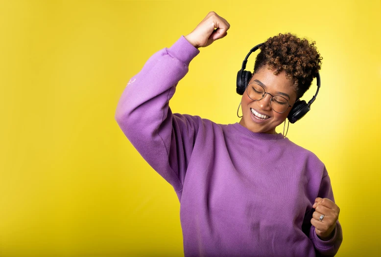 a woman wearing headphones gives a thumbs up