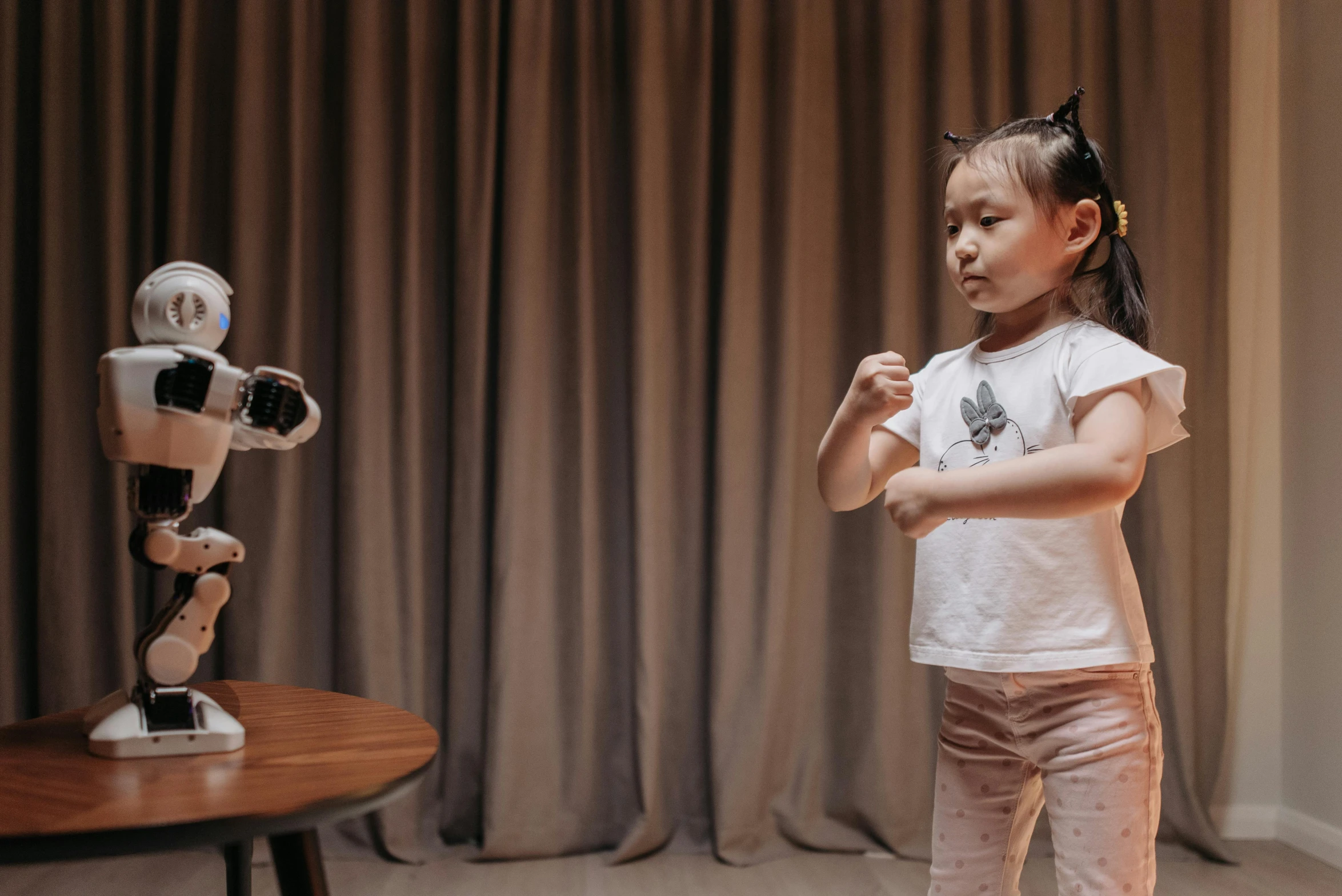 a little girl with a stuffed toy standing next to a robot