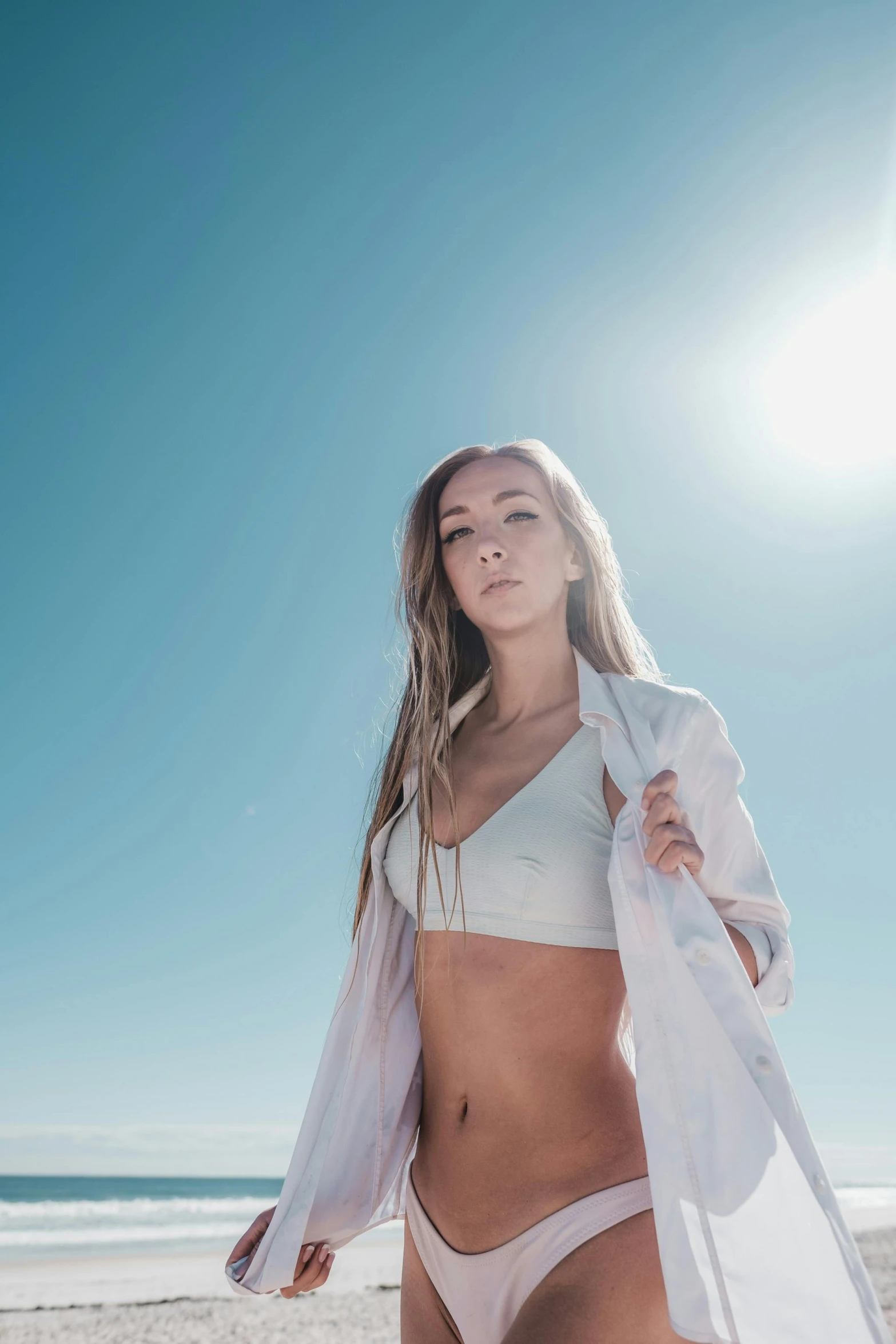 woman in bikini and sheer white shawl on the beach