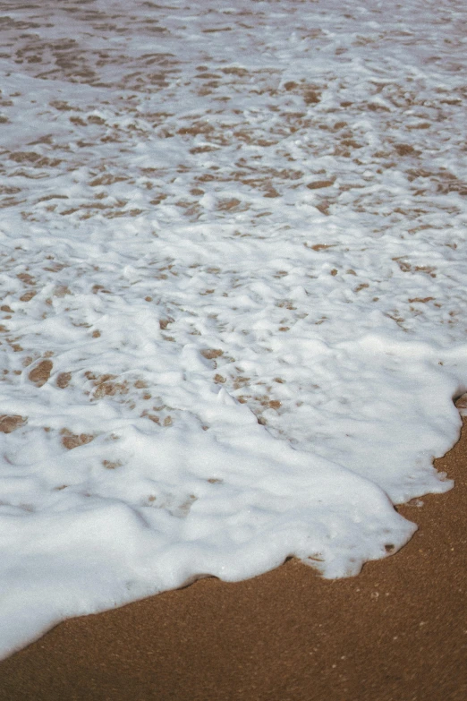 the white surf has foamy waves on the sand