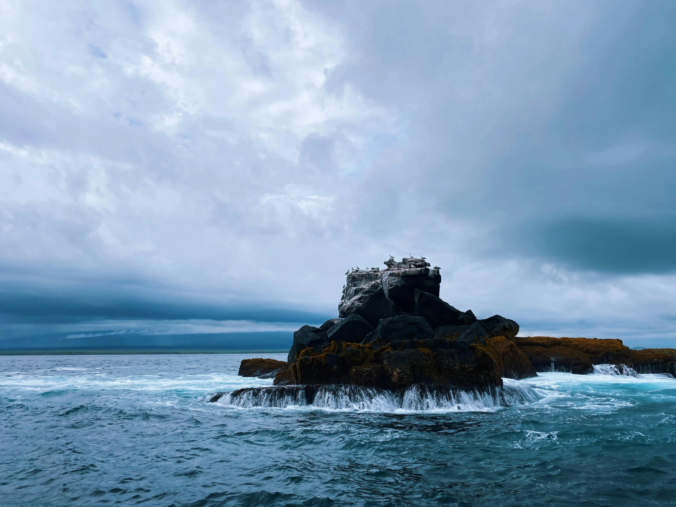 an island in the middle of the ocean with crashing waves