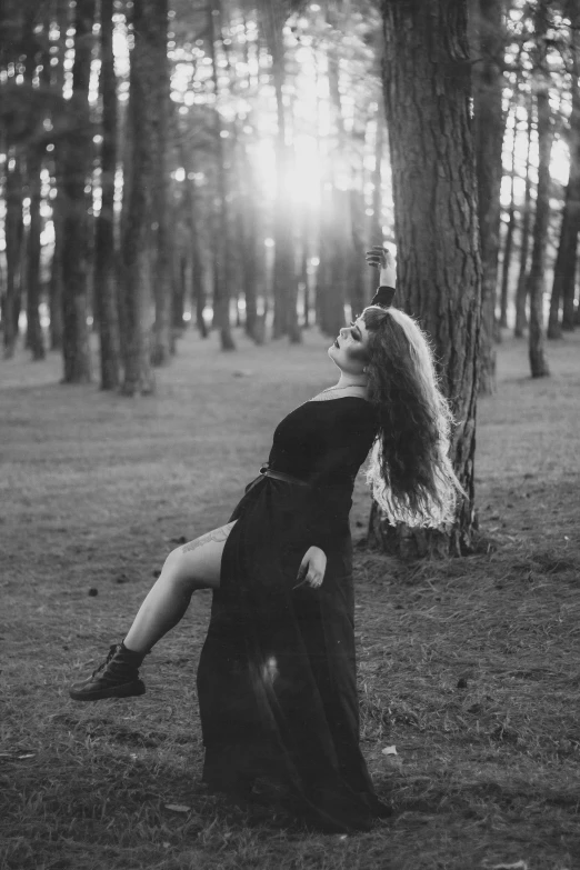 a woman laying in a black dress in the woods