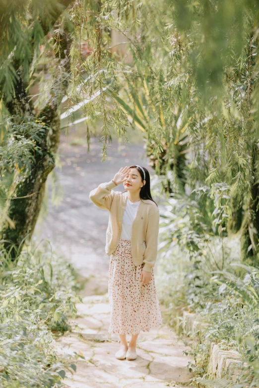 a woman looks up into a tree canopy