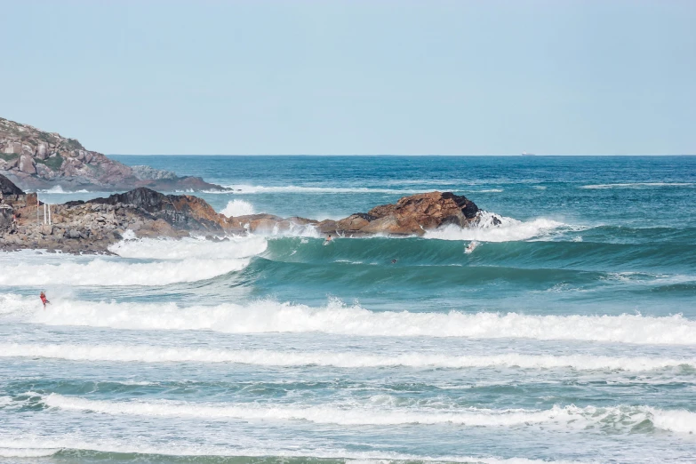 there is a wave that is crashing and a man stands in the ocean