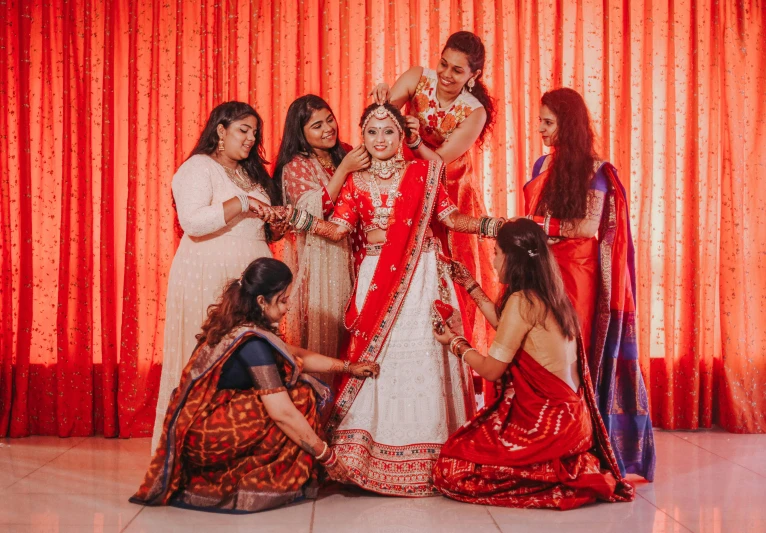 indian bride and bridesmaids getting dressed up in red and white outfits