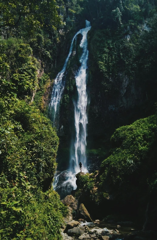 a man standing in front of a waterfall