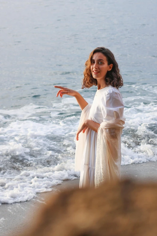 a lady that is standing in the sand and pointing