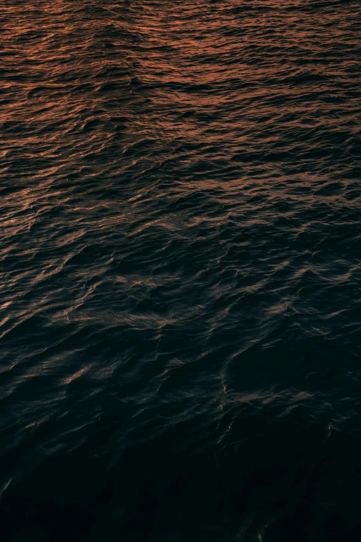 a boat floats in the ocean during a sunset