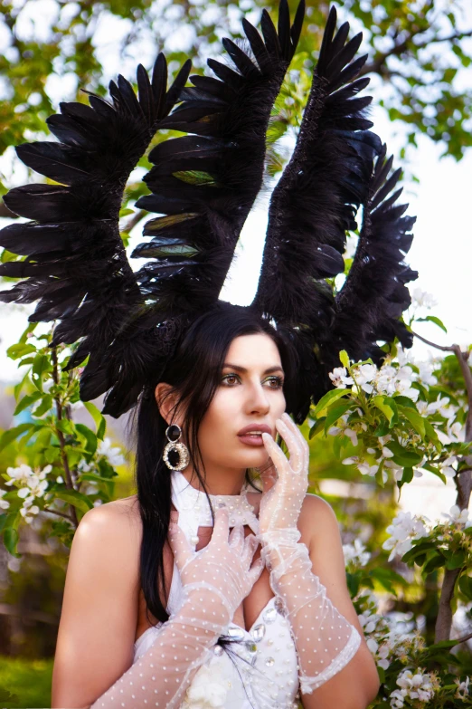 a woman wearing black feathers and gloves with flowers in front of her