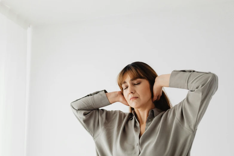 a woman is holding her head while wearing an shirt