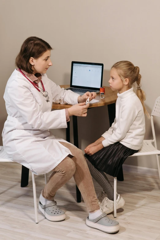 a woman is sitting at a desk with a little girl