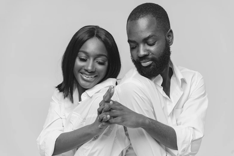 a black couple holding each other in front of a white wall