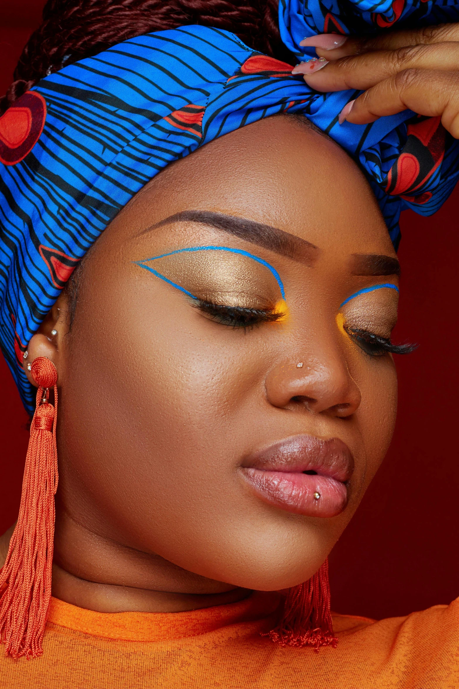 a woman wearing blue and orange with makeup on her face