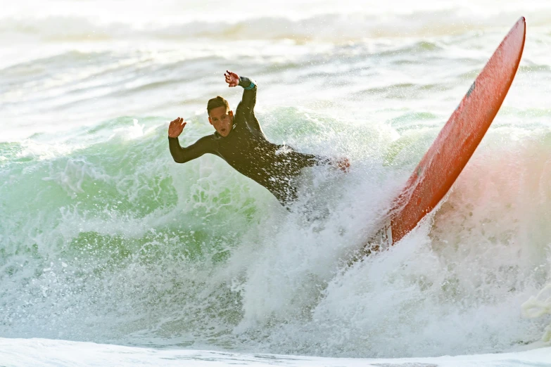 a person riding a red surf board on a wave