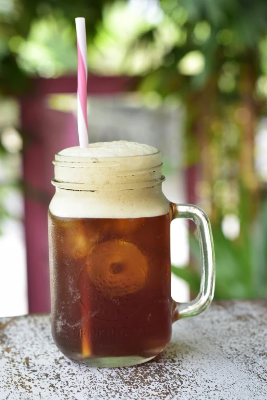 a brown cup of tea with a pink straw on top