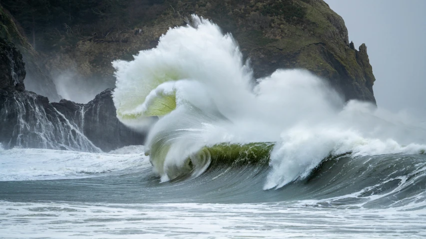 a large wave crashing into a rocky beach