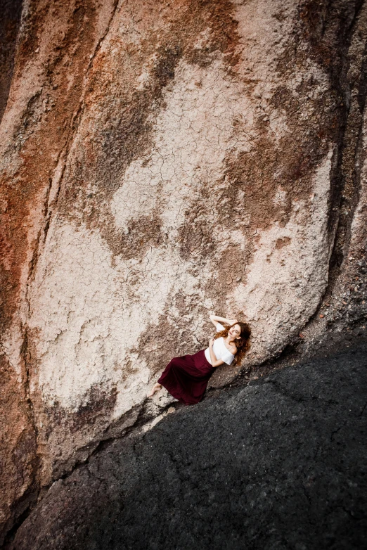 a woman is laying down on a rock