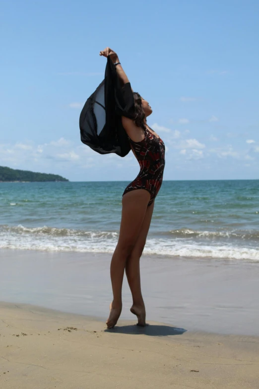 woman with black cloth on beach looking over water