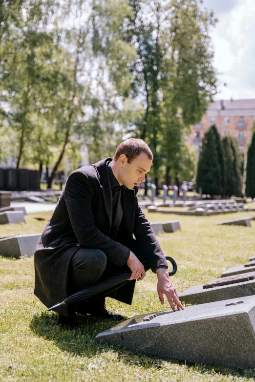 a man kneeling down near headstones for a war memorial