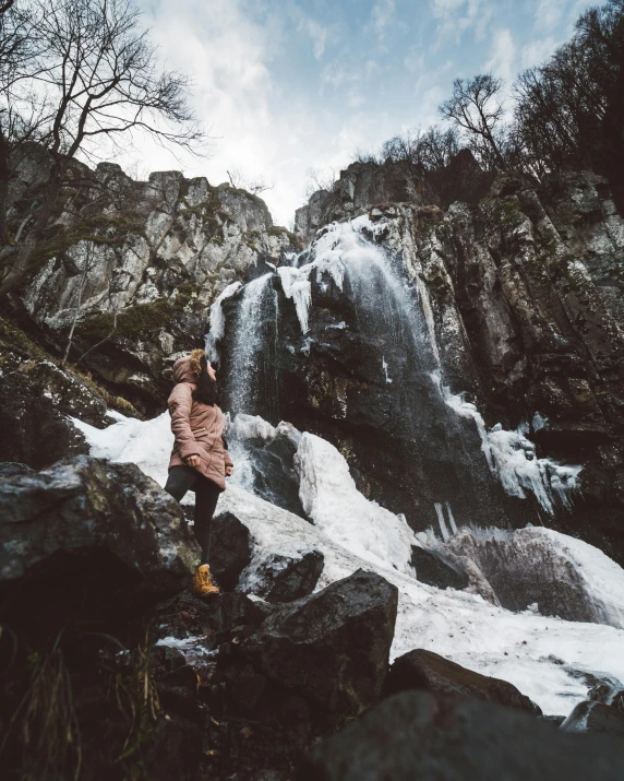 the young woman is standing by a waterfall