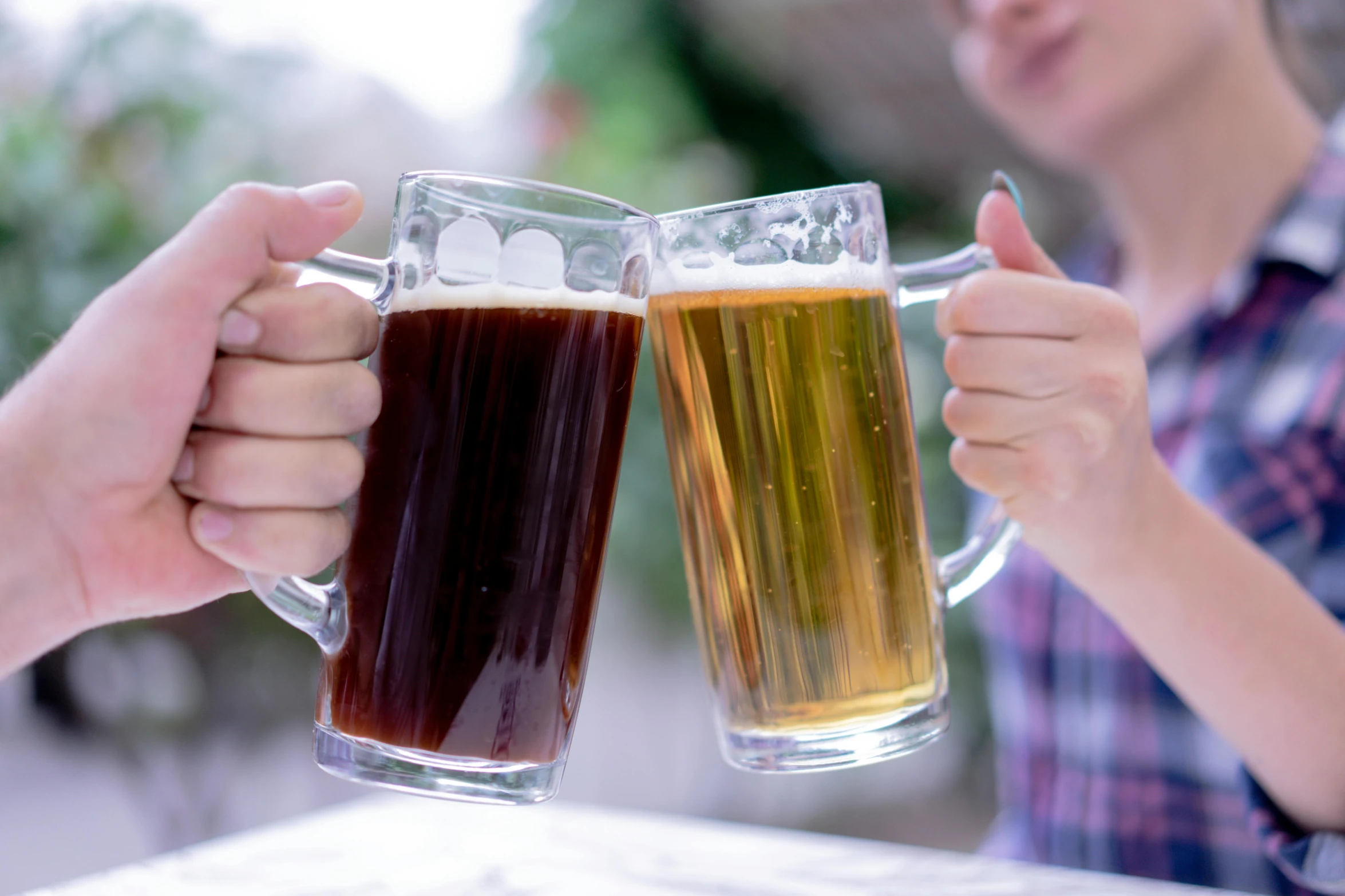 a pair of hands holding up beers that are sitting on a table