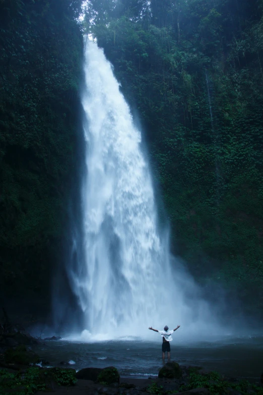 a man stands in front of a waterfall
