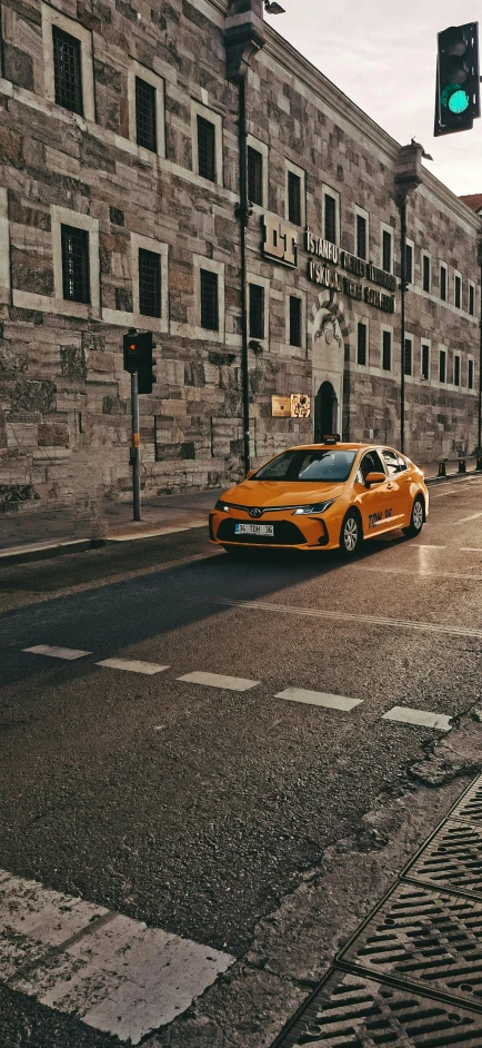 a orange car on street next to a green traffic light