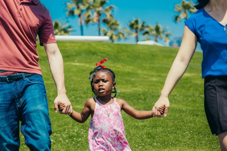 a family holding hands and walking in a grassy area