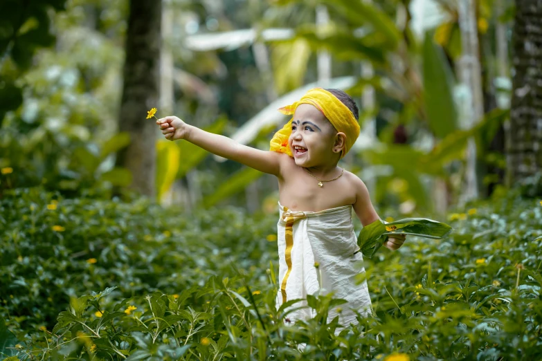 a child in a jungle is holding an orange flower