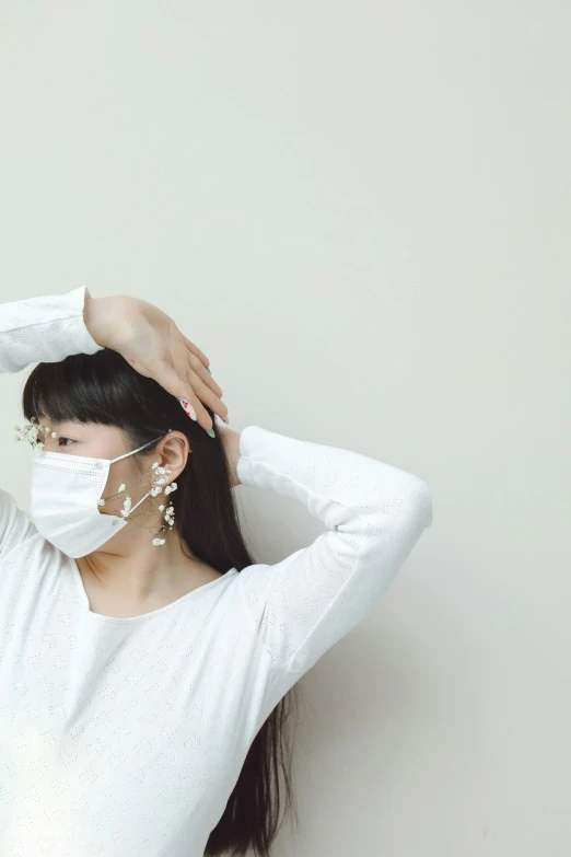 a girl wearing a face mask with her hair in her hand