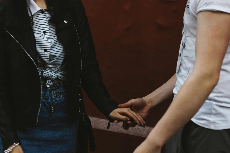 a beautiful woman standing next to a man near a wall