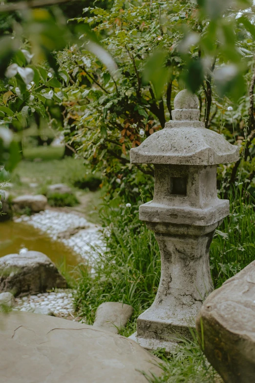 a lantern next to a small stream surrounded by green plants