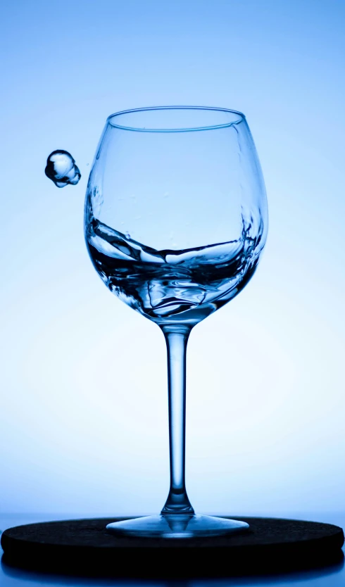 a wine glass is floating into water, reflecting the light on its rim