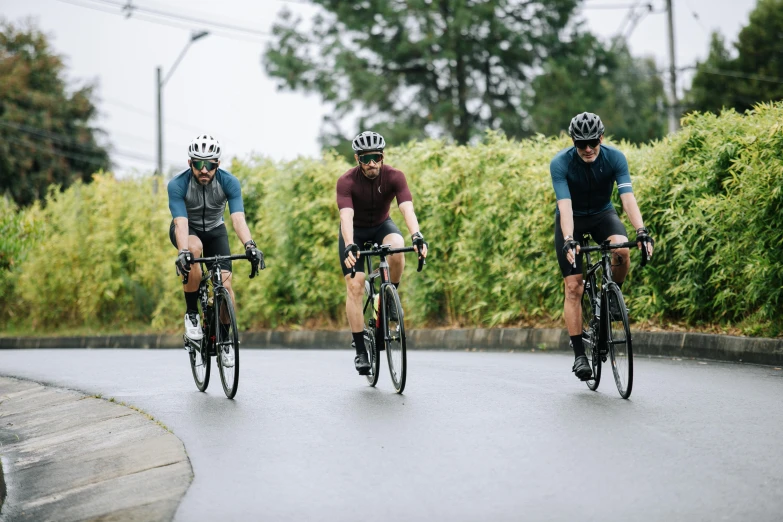 three men are riding their bicycles on a road