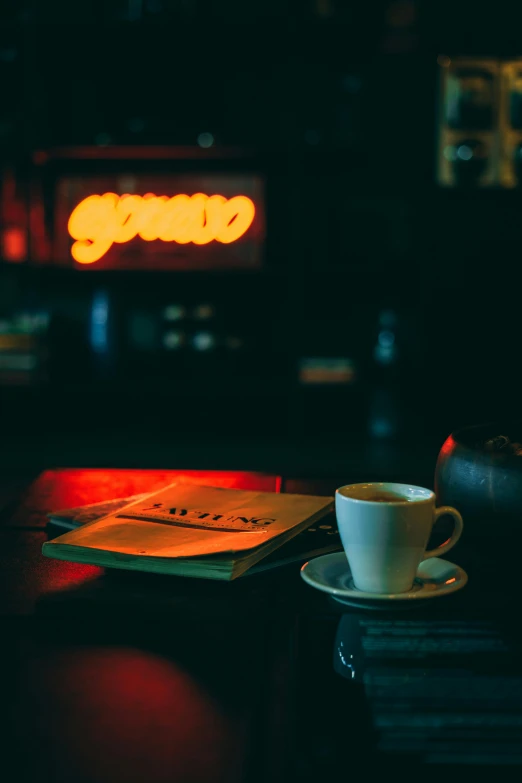 coffee cup with saucer and book on dark background