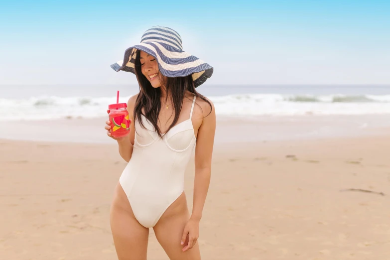 the woman with a blue and white hat is holding a drink