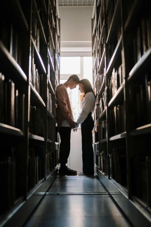 two people kissing in front of bookshelves