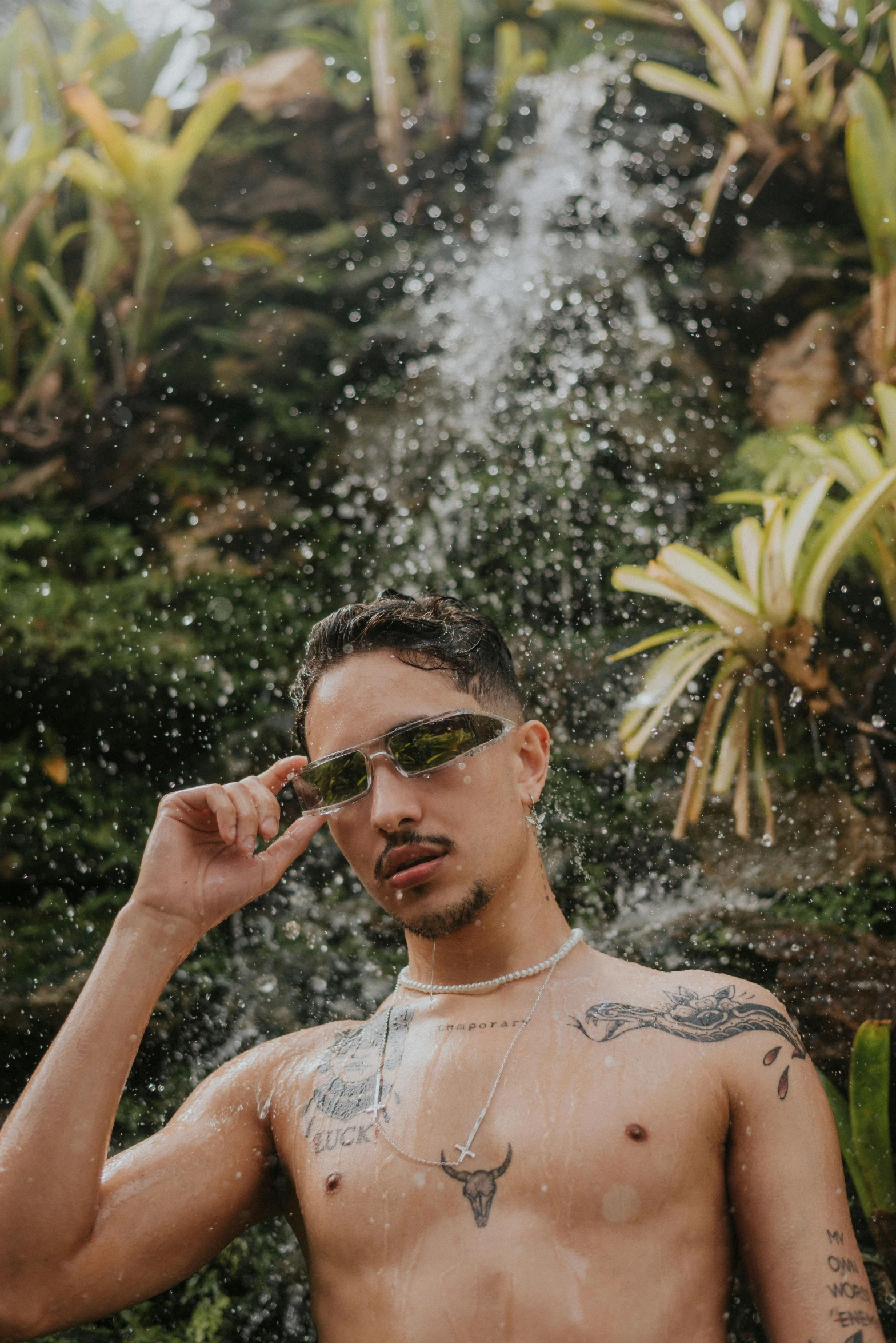 shirtless young man in shades with sunglasses and a waterfall