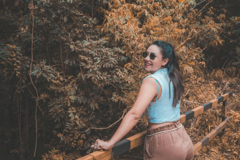 a woman wearing sunglasses standing by a fence